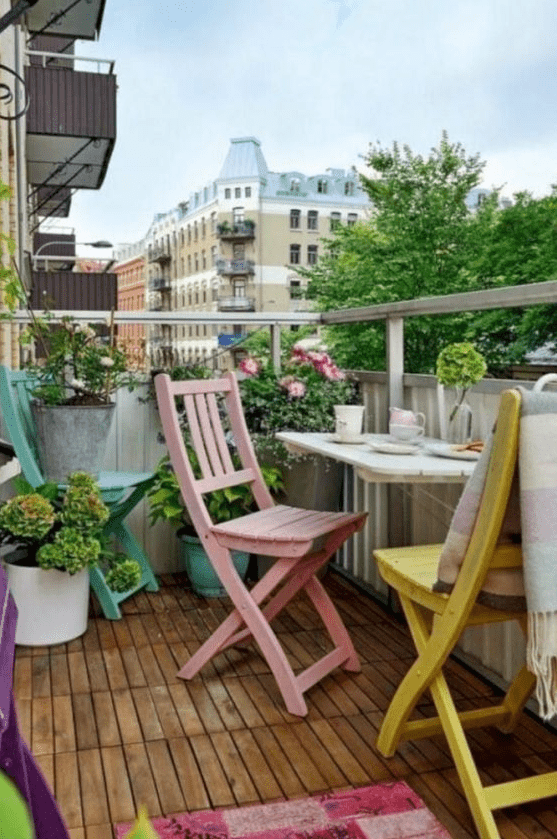 pastel chairs, a colorful rug, potted flowers and greenery for a comfy and chic spring balcony