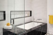 04 a bathtub placed into a black marble slab for a luxurious feel in the bathroom
