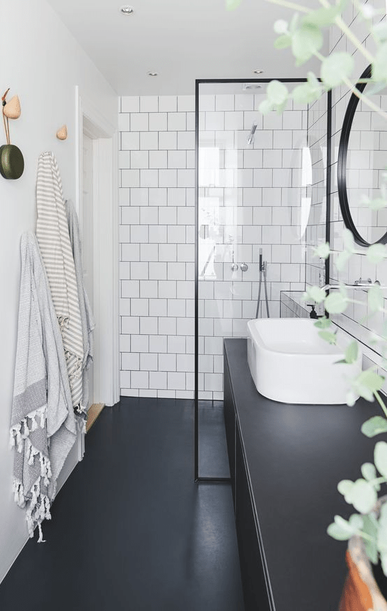 a Nordic bathroom with white square tiles, sleek black surfaces, black framing and a curved sink is very chic