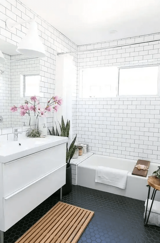 a bathroom clad with subway tiles accented with black grout and black hexagon tiles on the floor is trendy