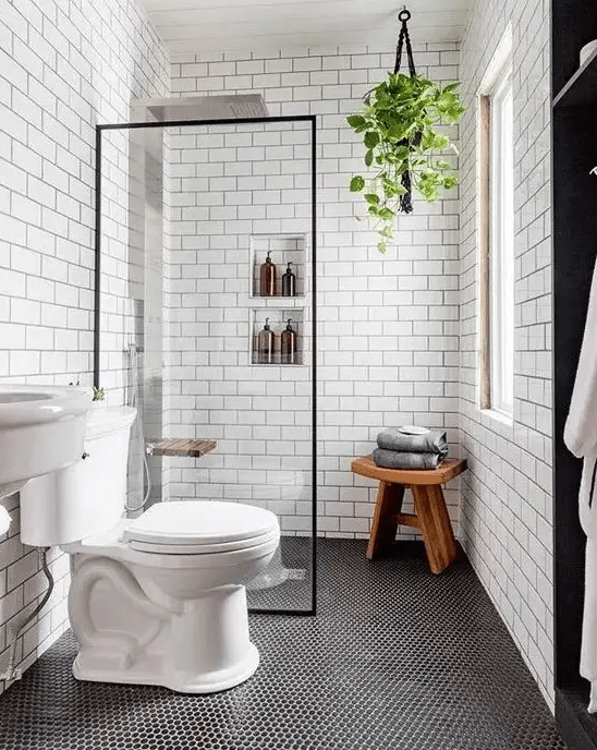 A contemporary bathroom with penny and subway tiles, built in shelves, a sink and a wooden stool