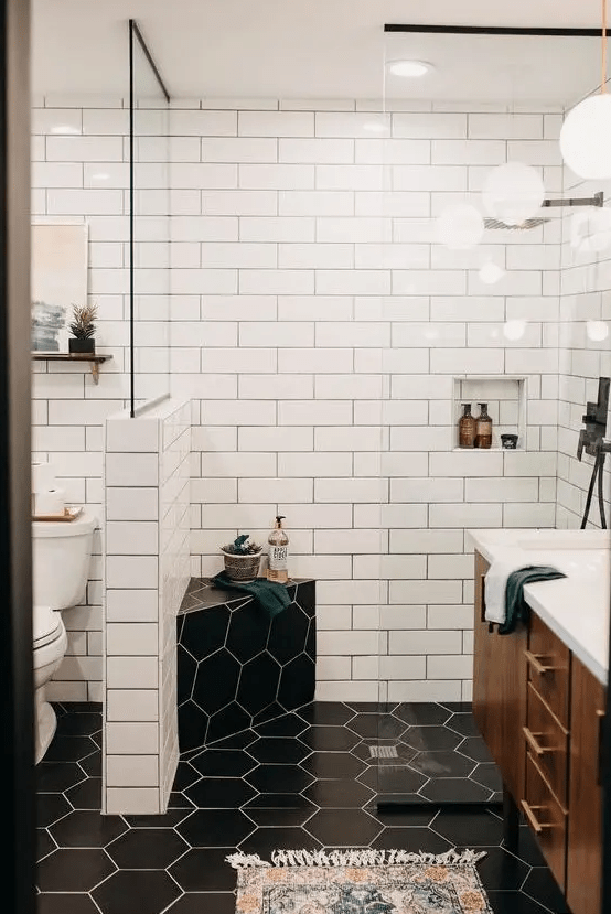 A contrasting mid century modern bathroom with white subway and black hex tiles, a rich stained vanity and touches of gold