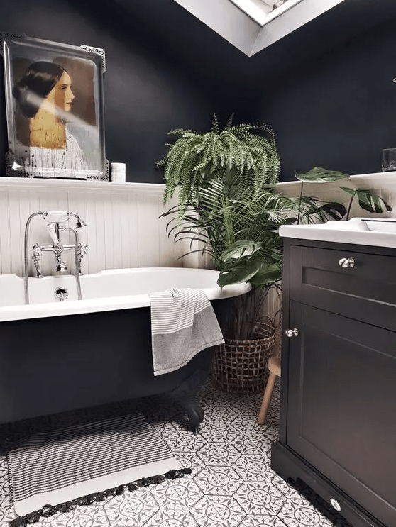 a lovely modern bathroom with black walls, white planks, a black vanity, a black tub, patterned tiles, a skylight and an artwork
