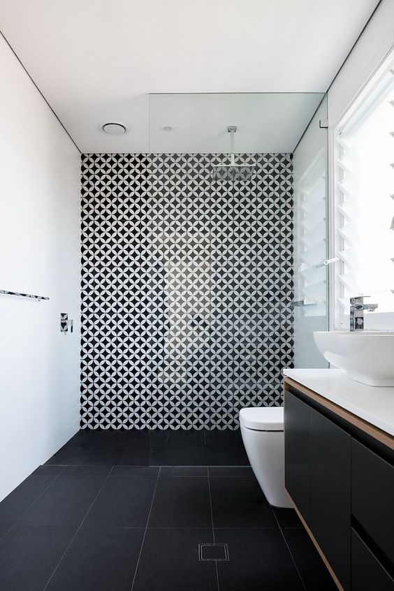 a minimalist bathroom with a black tile floor, white walls and a geo accent wall, a black vanity and white appliances