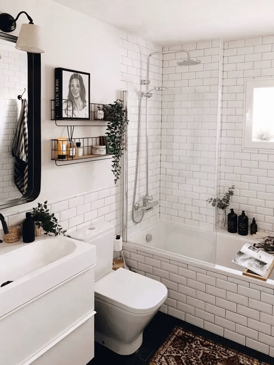 a modern Scandi bathroom with white subway tiles, a white vanity with a sink, shelves, a mirror with a lamp