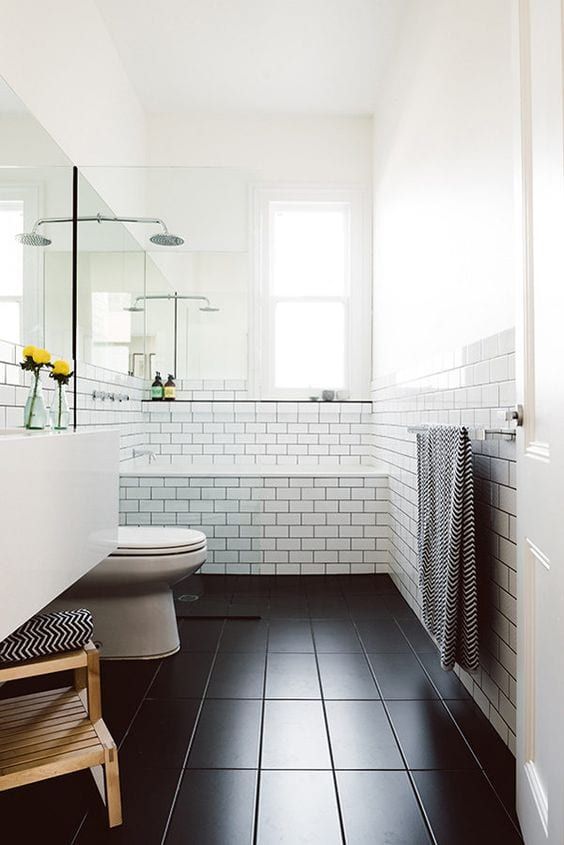 a modern bathroom with white subway tiles and black ones on the floor, a white appliances and stained ladder