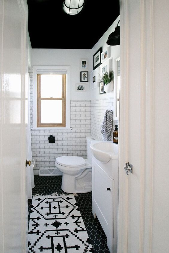 a small black and white bathroom with a black ceiling, white walls, a tub, white appliances, a white vanity and a black and white floor