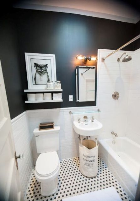 A small black and white bathroom with black walls, a bathtub space clad with white tiles, a wall mounted sink and some decor
