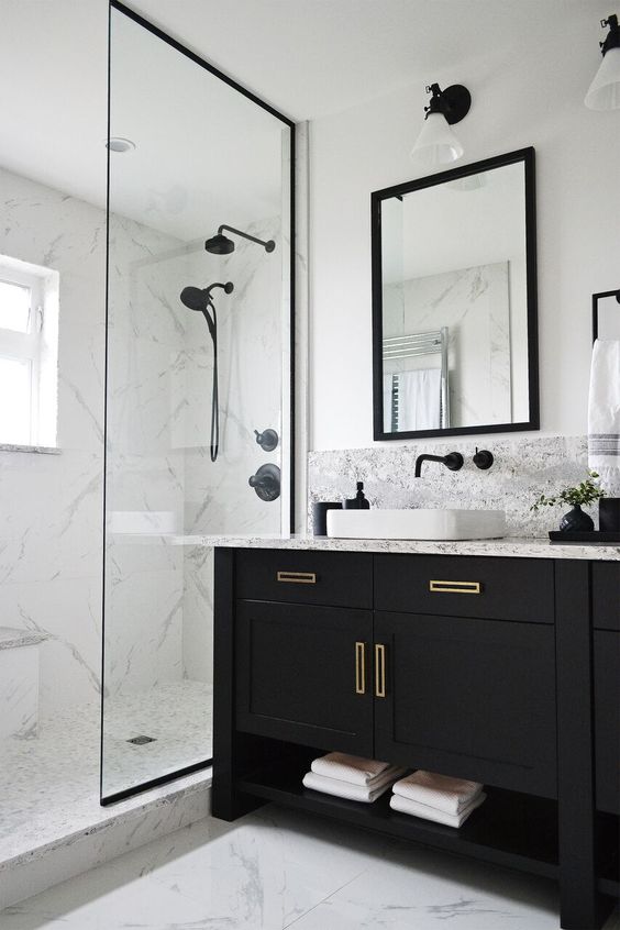 a small modern bathroom with white marble, a black vanity, black fixtures and a mirror in a black frame