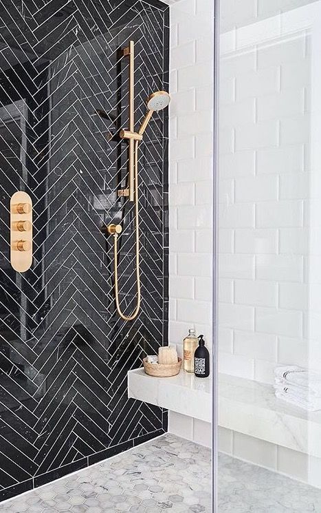 a statement wall of black tiles clad in a chevron pattern and done with white grout for an elegant feel