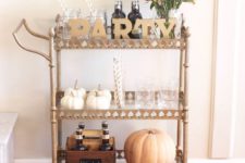 04 party hard this fall with a bar cart with a bright floral arrangement, gold letters and real pumpkins
