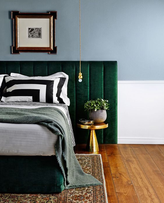 an upholstered emerald bed is highlighted with bright gold touches for a chic look