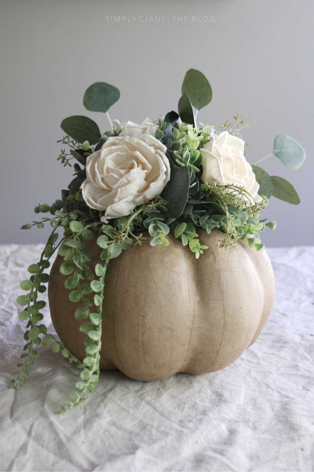 DIY craft pumpkin centerpiece with neutral blooms and greenery