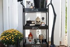 a black bar cart with witches’ legs, skulls, a black bird and a broom for a bold look