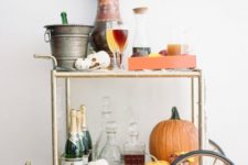 a bright Thanksgiving bar cart with pumpkins, bright flowers and colorful drinks on the cart