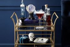 a simple yet very refined bar cart with fabric pumpkins, candles, skulls and a glass ball