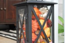 a vintage lantern filled with fake leaves and pumpkins in bold colors will last long and is easy to make