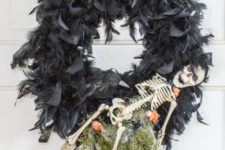 DIY creepy Halloween wreath of black feathers, a skeleton and some greenery