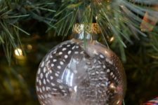 03 a modern holiday ornament of clear glass filled with guinea feathers is a fun idea you can easily DIY