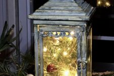 12 a shabby chic lantern with evergreens, ornaments and lights is a very festive-like idea