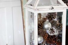 14 a white lantern with pinecones, ornaments and star-shaped lights for winter holidays