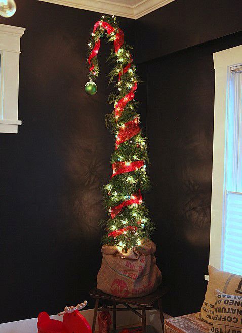a tall Grinch Christmas tree decorated with lights and red burlap plus a single green ornament on top