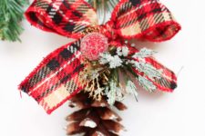 DIY pinecone ornaments with plaid ribbon bows and fake greenery and berries