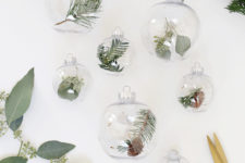 DIY clear Christmas ornaments filled with greenery and little pinecones