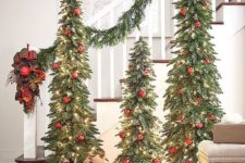 09 a chic trio of Christmas trees with lights and red ornaments plus a matching garland is a bold idea