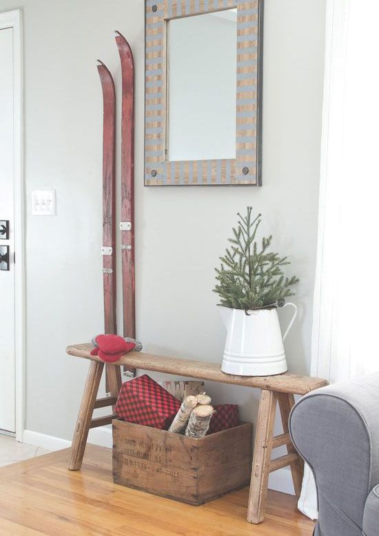 a vintage rustic entryway styled with a wooden box with firewood and red vintage skis is a very cozy space