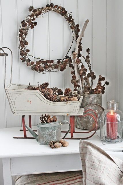 a vintage decorative sledge filled with pinecones, a pinecone wreath and an arrangement in a basket for a rustic feel