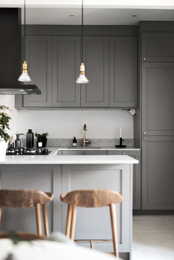 a simple contemporary space done in grey, with a white backsplash, stone countertops and metallic touches