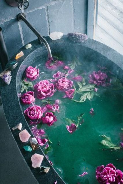 a bathtub filled with fuchsia blooms and with geodes placed on the edge of each bathtub