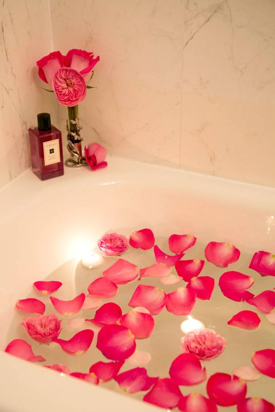 pink petals and peonies in the bath, floating candles, a bloom arrangement on the corner of the bathtub