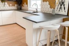 a Scandinavian kitchen with terracotta walls, white sleek cabients, concrete countertops, an eye-catchy hexagon tile backsplash