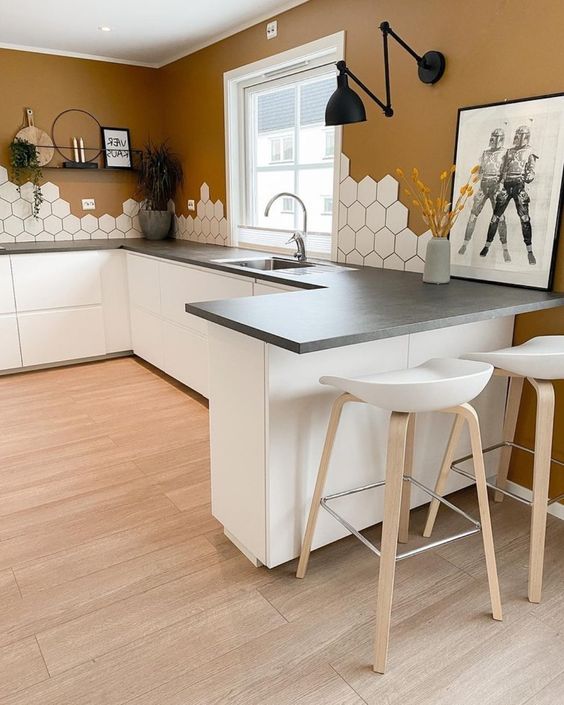 A Scandinavian kitchen with terracotta walls, white sleek cabients, concrete countertops, an eye catchy hexagon tile backsplash