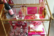 a bar cart styled in hot pink – with hearts, bottles, drink stirrers and fun candies for Valentine’s Day