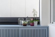 a beautiful blue planked screen with sliding doors is a lovely way to hide a radiator and add a soft touch of color to the space