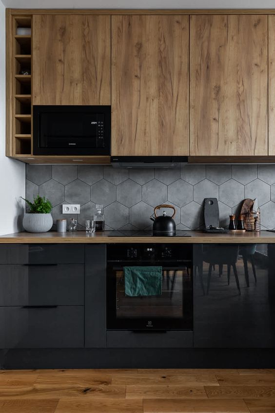 a black and stained kitchen with butcherblock countertops, a grey hexagon tile backsplash and black appliances