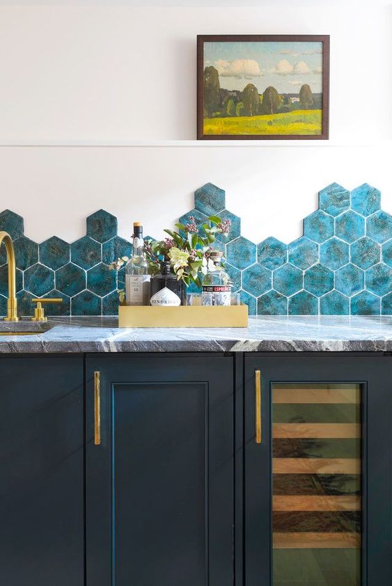 a bold navy kitchen with grey marble countertops and bold blue hexagon tiles plus gold fixtures is adorable