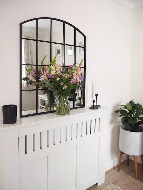 a creative radiator cover of wooden panels and a planked touch as a console table with a mirror, candles and blooms