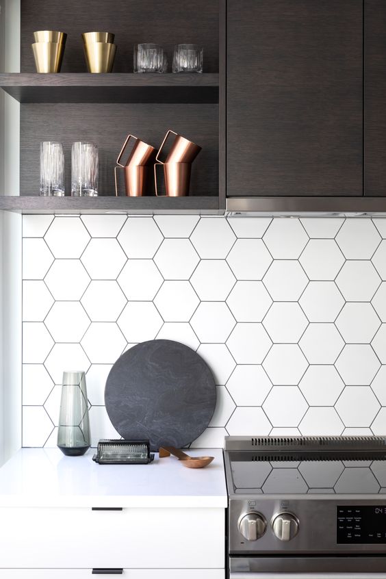 A dark stained and white kitchen with a white hexagon tile backsplash and white countertops looks very stylish