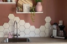 a eye-catchy kitchen with sleek white cabinets, butcherblock countertops, a hexagon tile backsplash and burgundy walls