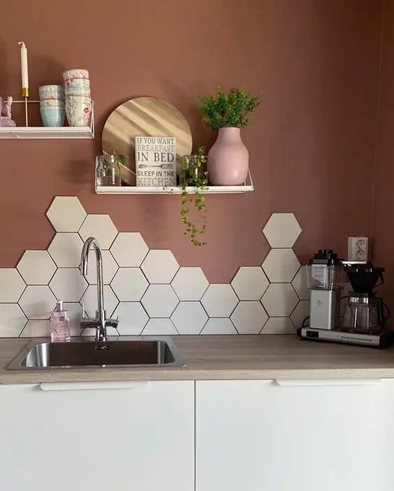 A eye catchy kitchen with sleek white cabinets, butcherblock countertops, a hexagon tile backsplash and burgundy walls
