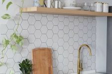 a light grey kitchen with white stone countertops, open shelves, a white hexagon tile backsplash and greenery