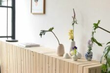 a light-stained planked radiator cover with vases and blooms is a cool console table for an entryway