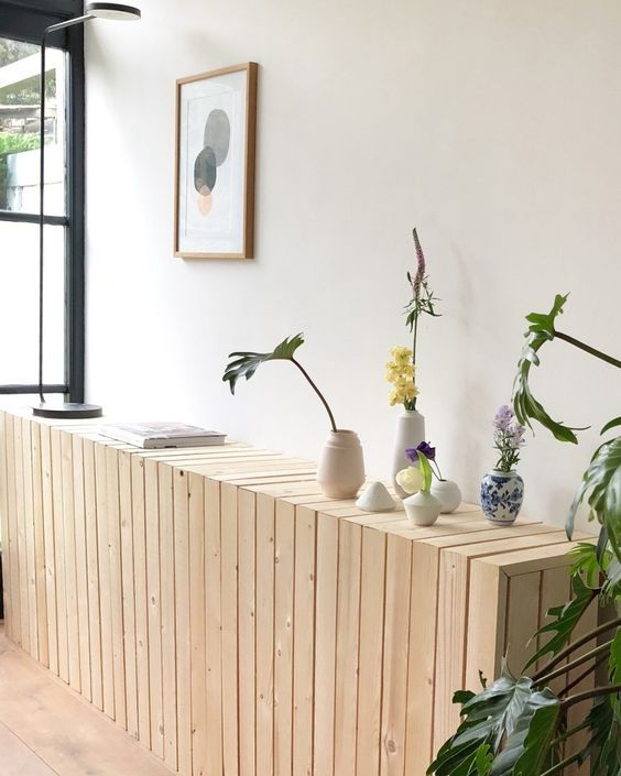 a light-stained planked radiator cover with vases and blooms is a cool console table for an entryway