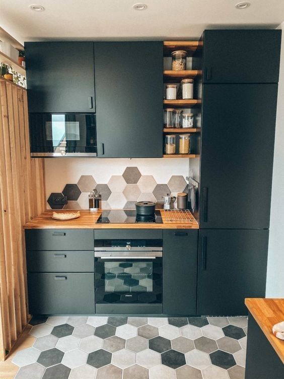 a matte black kitchen with butcherblock countertops, open shelves, grey, tan and beige hexagon tiles on the wall and floor