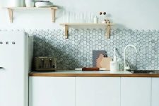 a minimalist white kitchen with wooden touches and a grey marble hexagon tile backsplash