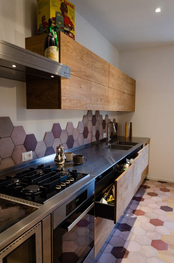 a modern stained kitchen with metal countertops and a bold pink and burgundy hexagon tile backsplash and floor